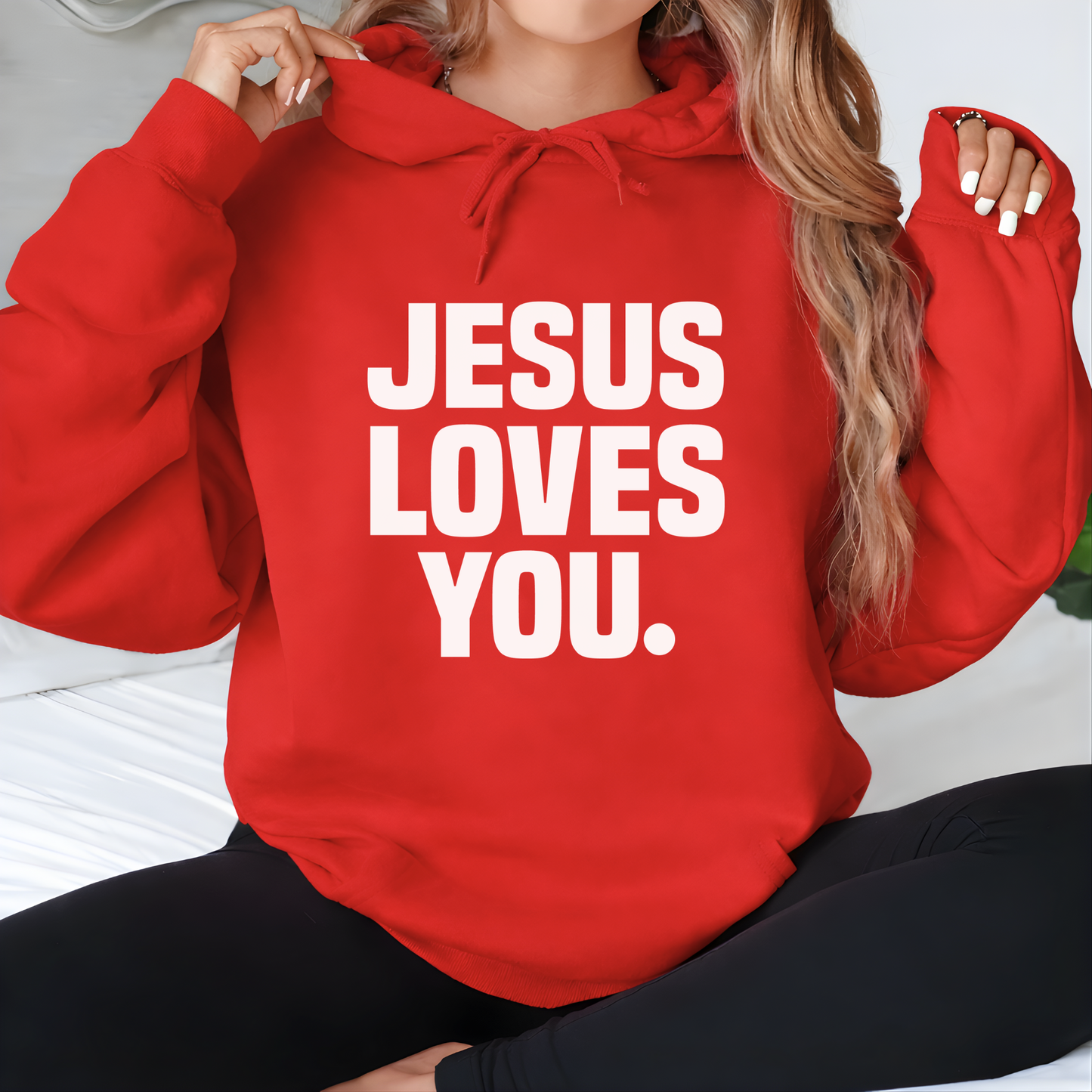 Person wearing a red hoodie with 'Jesus Loves You' text.