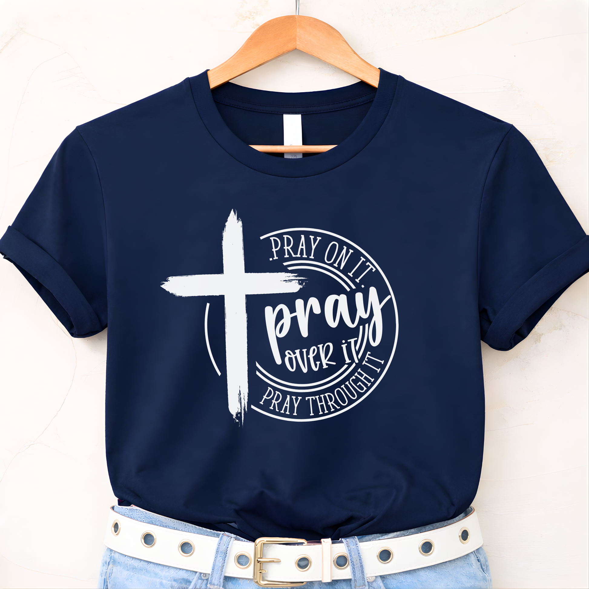 Navy blue t-shirt with a white cross and text on a hanger against a white background