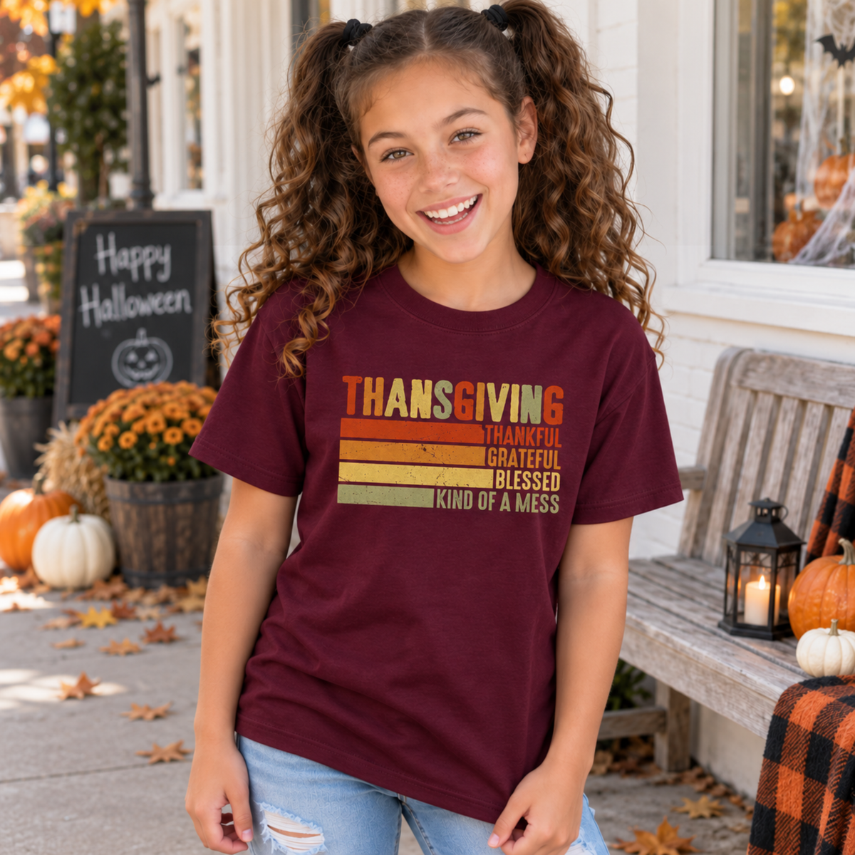 Girl wearing a maroon youth T-shirt with retro Thanksgiving Kind of a Mess design outside a fall storefront.