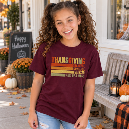 Girl wearing a maroon youth T-shirt with retro Thanksgiving Kind of a Mess design outside a fall storefront.