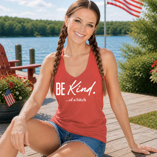 Woman wearing a red tank top with 'BE KIND...of a bitch' text by a lake.