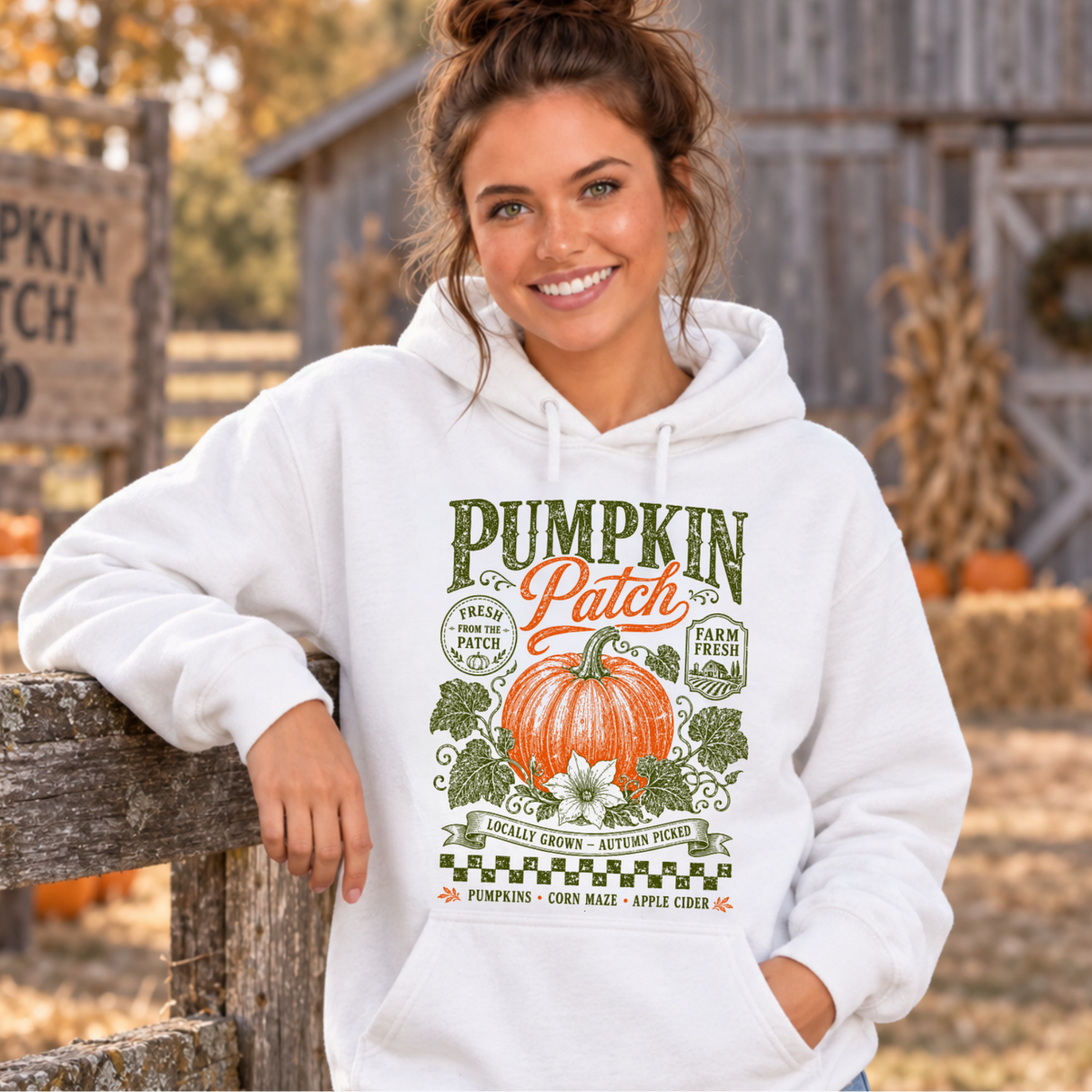 Woman wearing a white hoodie with vintage Pumpkin Patch pumpkin and floral design at a rustic fall pumpkin farm