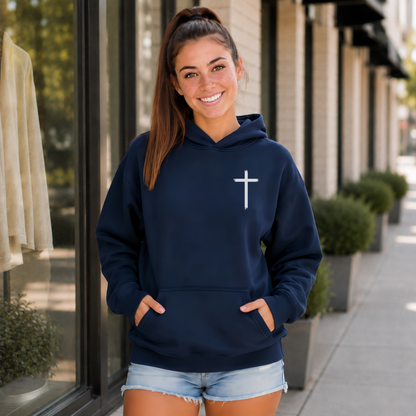 Woman wearing a navy hoodie with a white cross on the front chest outside a storefront.