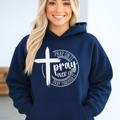 Person wearing a navy blue hoodie with a cross and text design on a plain background