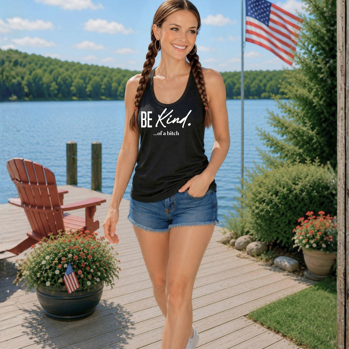 Woman wearing a black tank top with 'BE KIND' text by a lake
