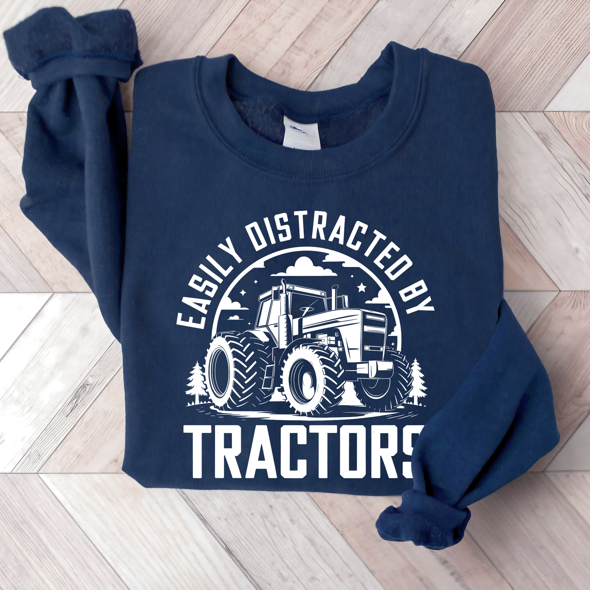 Navy blue sweatshirt with tractor graphic and text on a wooden floor
