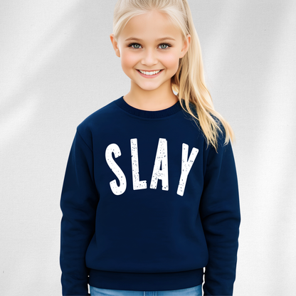 Young girl wearing a navy blue sweatshirt with 'SLAY' printed on it against a plain background