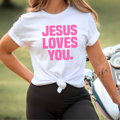 Person wearing a white t-shirt with 'Jesus Loves You' in pink text, standing next to a motorcycle.