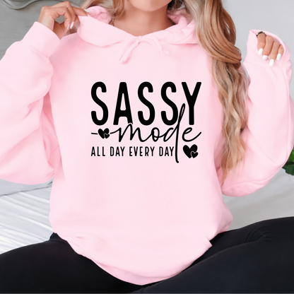 Pink hoodie with 'Sassy mode all day every day' text worn by a Woman .