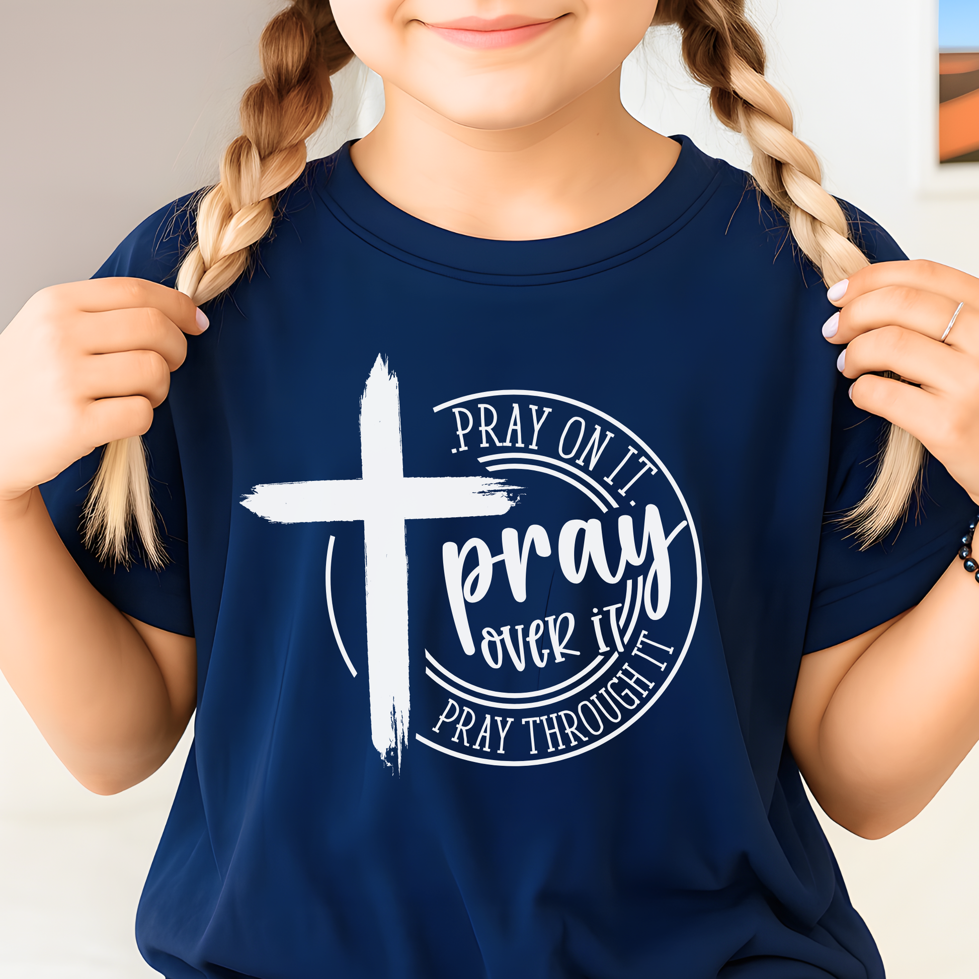 Child wearing a navy blue t-shirt with a white cross and text design.
