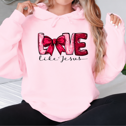 Woman wearing a Love Like Jesus light pink hoodie with pink bow graphic
