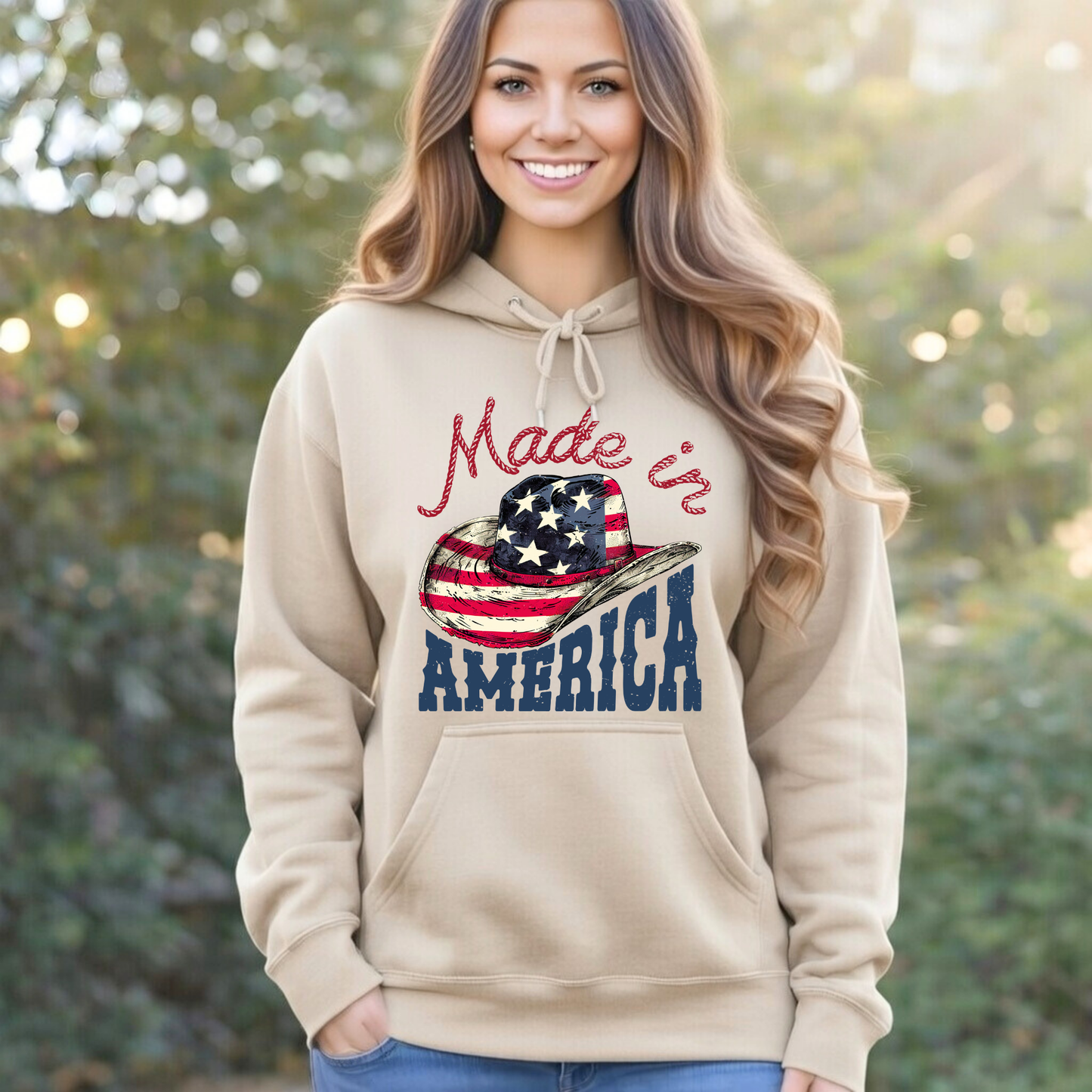 Woman wearing a beige hoodie with 'Made in America' graphic, standing outdoors.
