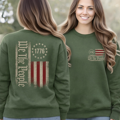 Green sweatshirt with 'We The People' text and flag design, worn by a woman outdoors.