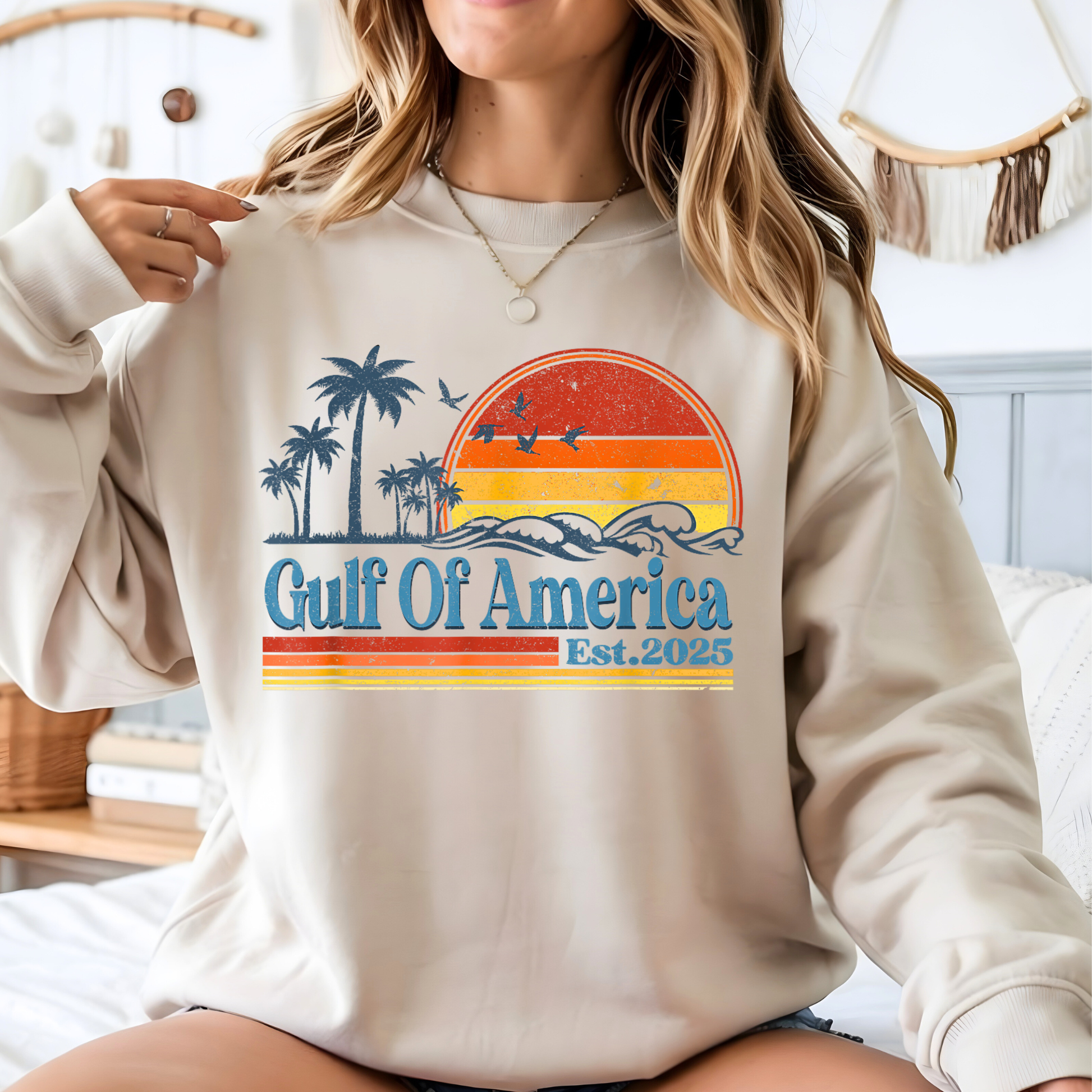 Woman wearing a beige sweatshirt with 'Gulf Of America Est. 2025' design.