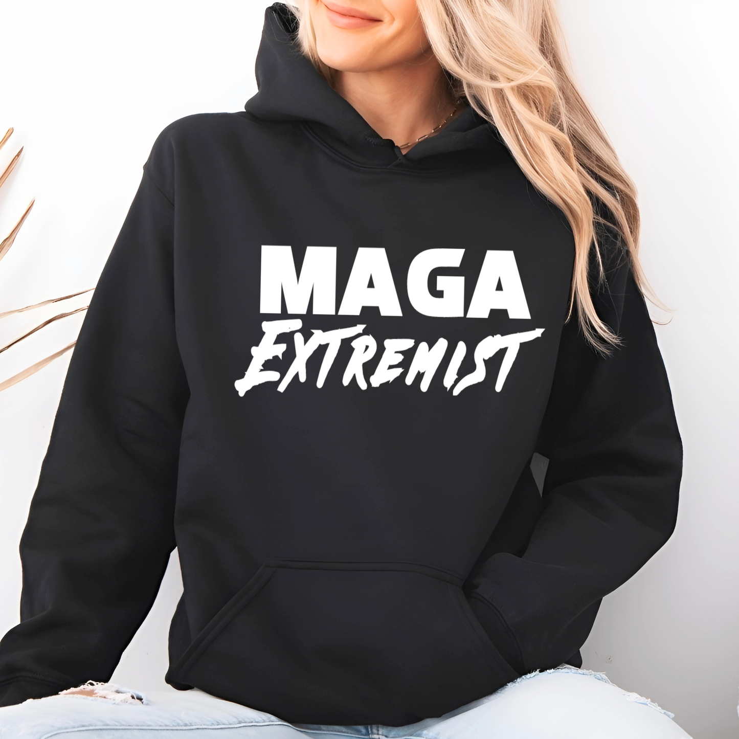 Woman wearing black MAGA Extremist hoodie seated casually, relaxed fit political hoodie
