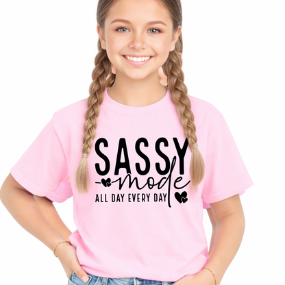 Young girl wearing a pink t-shirt with 'Sassy mode all day every day' text on a white background