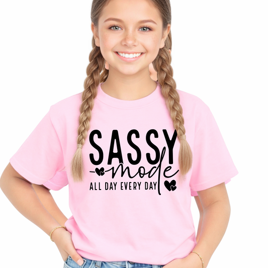 Young girl wearing a pink t-shirt with 'Sassy mode all day every day' text on a white background
