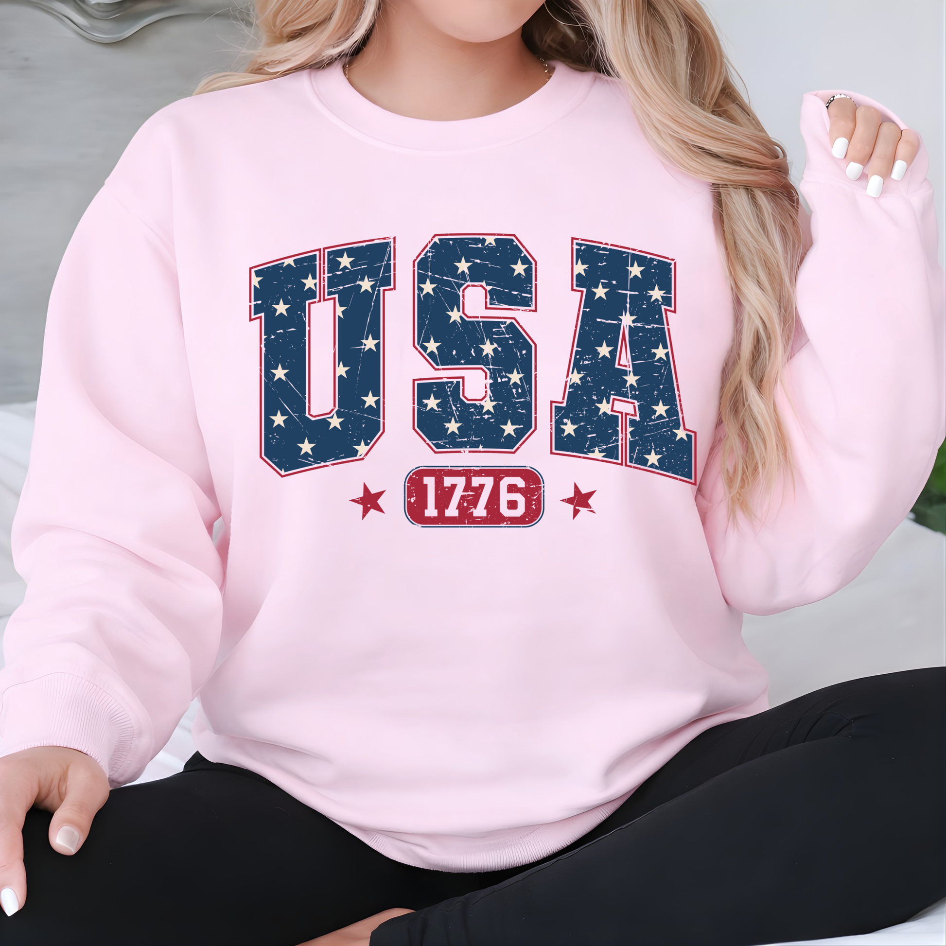 Woman wearing a pink sweatshirt with 'USA 1776' design