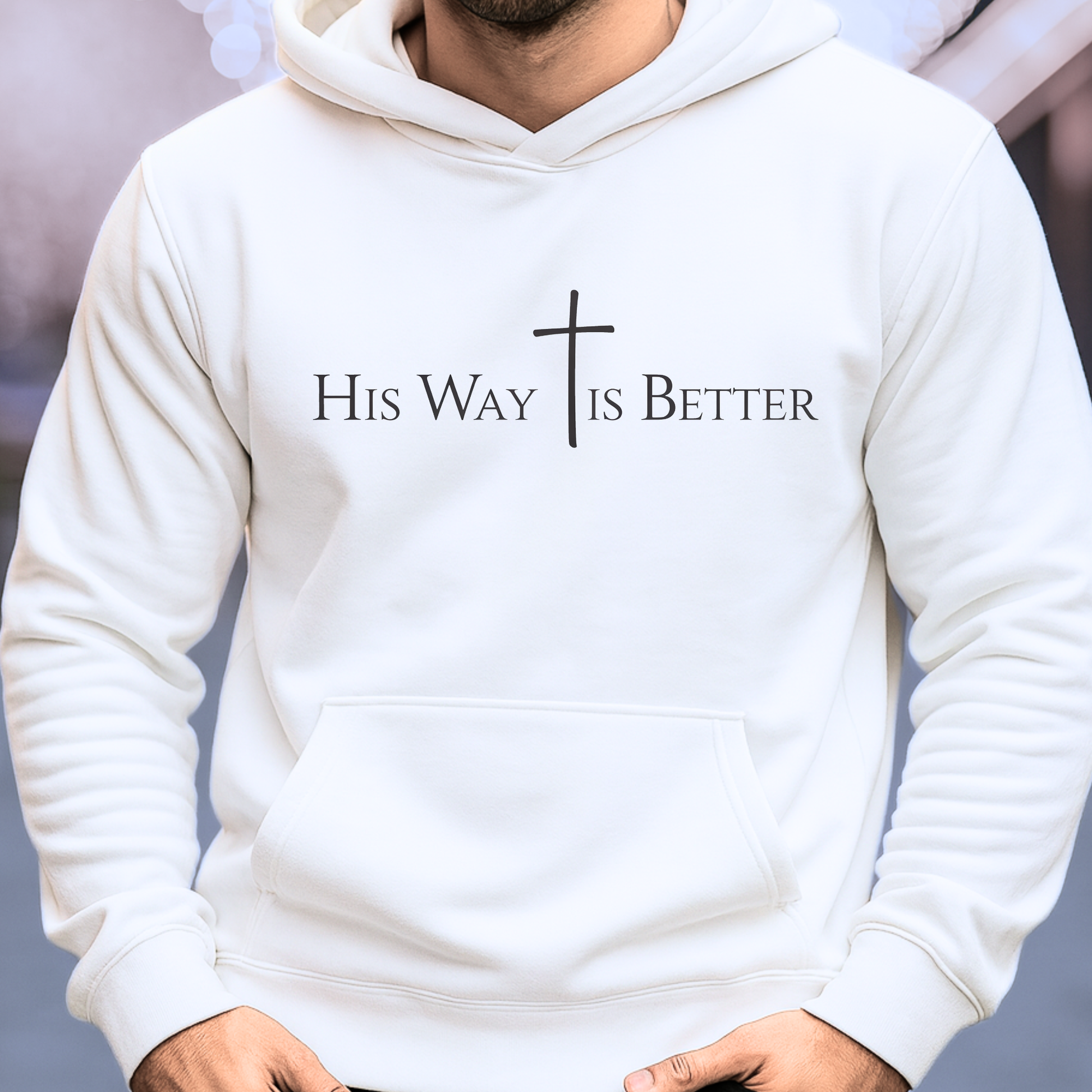 White hoodie with 'His Way Is Better' text and cross design on a blurred background