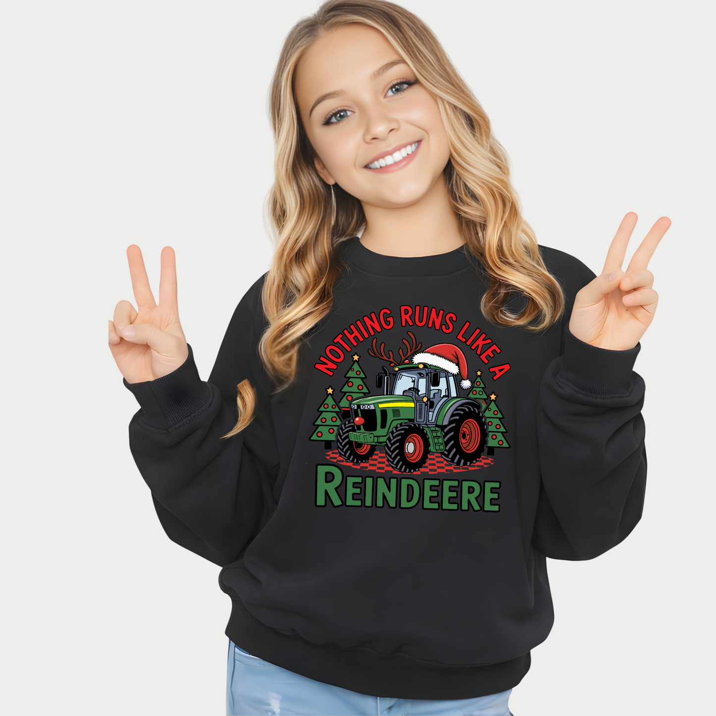 Young girl wearing a black sweatshirt with a Christmas-themed design and text, making peace signs.