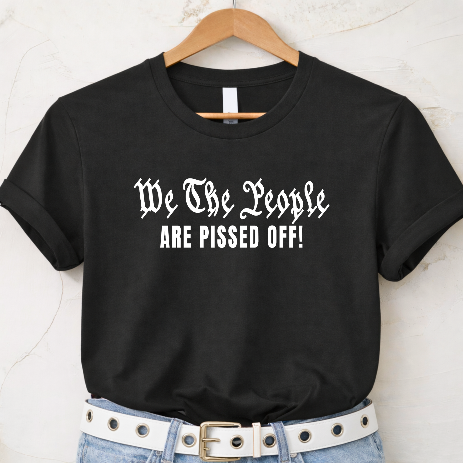 Black t-shirt with 'We The People ARE PISSED OFF!' text on a hanger.