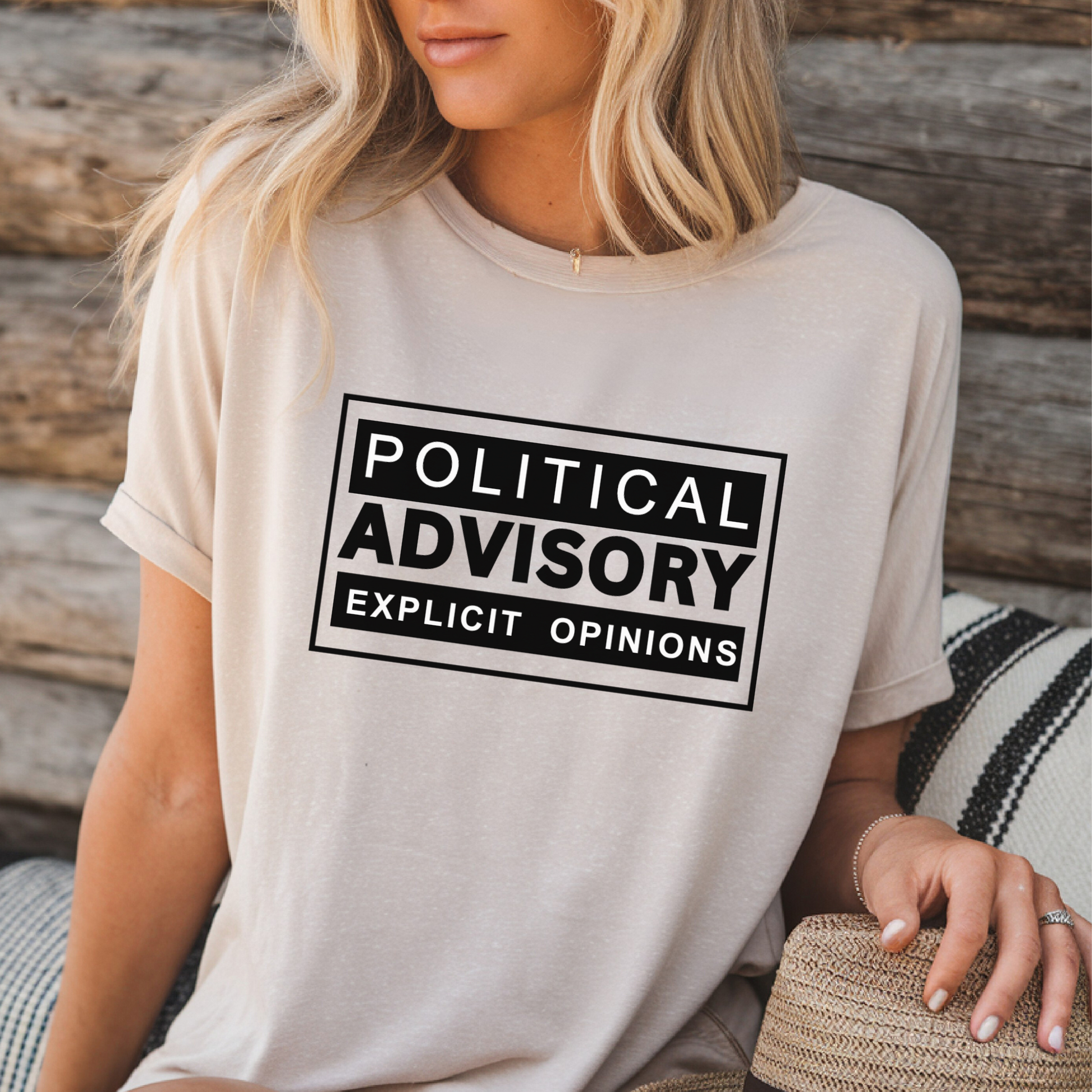 Woman wearing gray conservative “Political Advisory” t-shirt with black print, rolled sleeves and jeans.