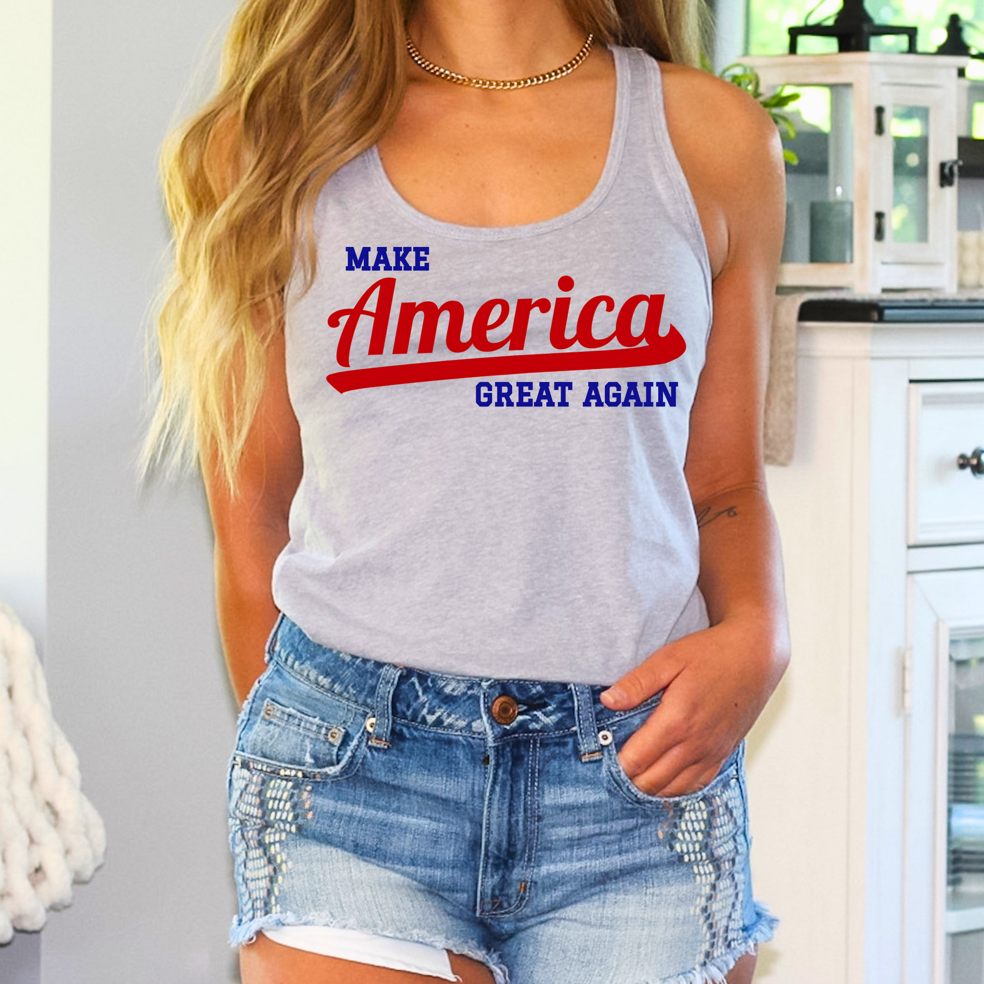 Young woman showing off a gray Make America Great Again racerback tank top in a casual outdoor setting