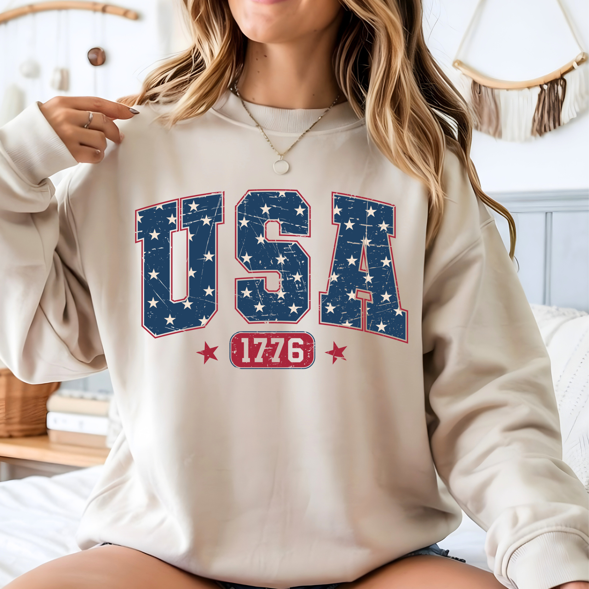 Person wearing a beige sweatshirt with 'USA 1776' text and star design.