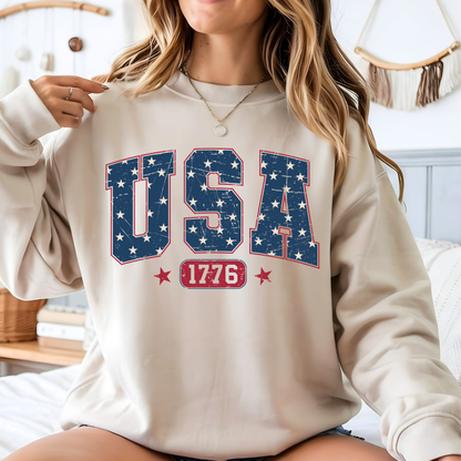 Person wearing a beige sweatshirt with 'USA 1776' text and star design.