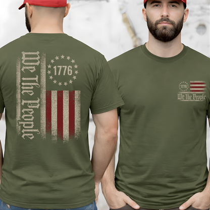 Man wearing an olive green t-shirt with 'We The People' and 1776 design on a plain background