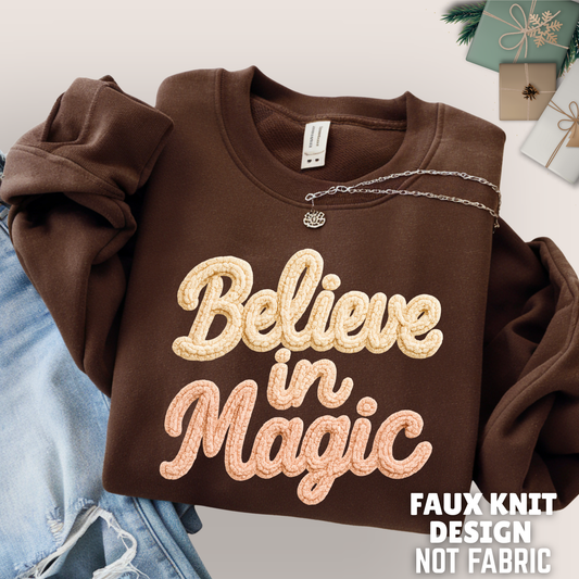 Brown sweatshirt flat lay with Believe in Magic faux crochet faux knit printed design, cozy Christmas crewneck, Black Friday holiday clothing.