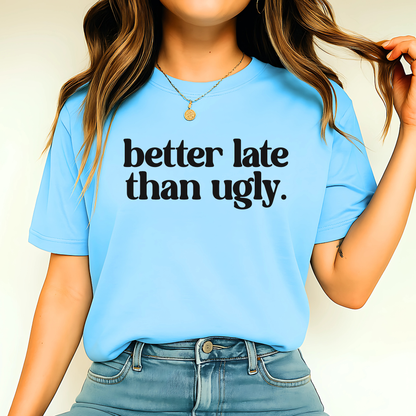 Person wearing a blue t-shirt with 'better late than ugly' text.