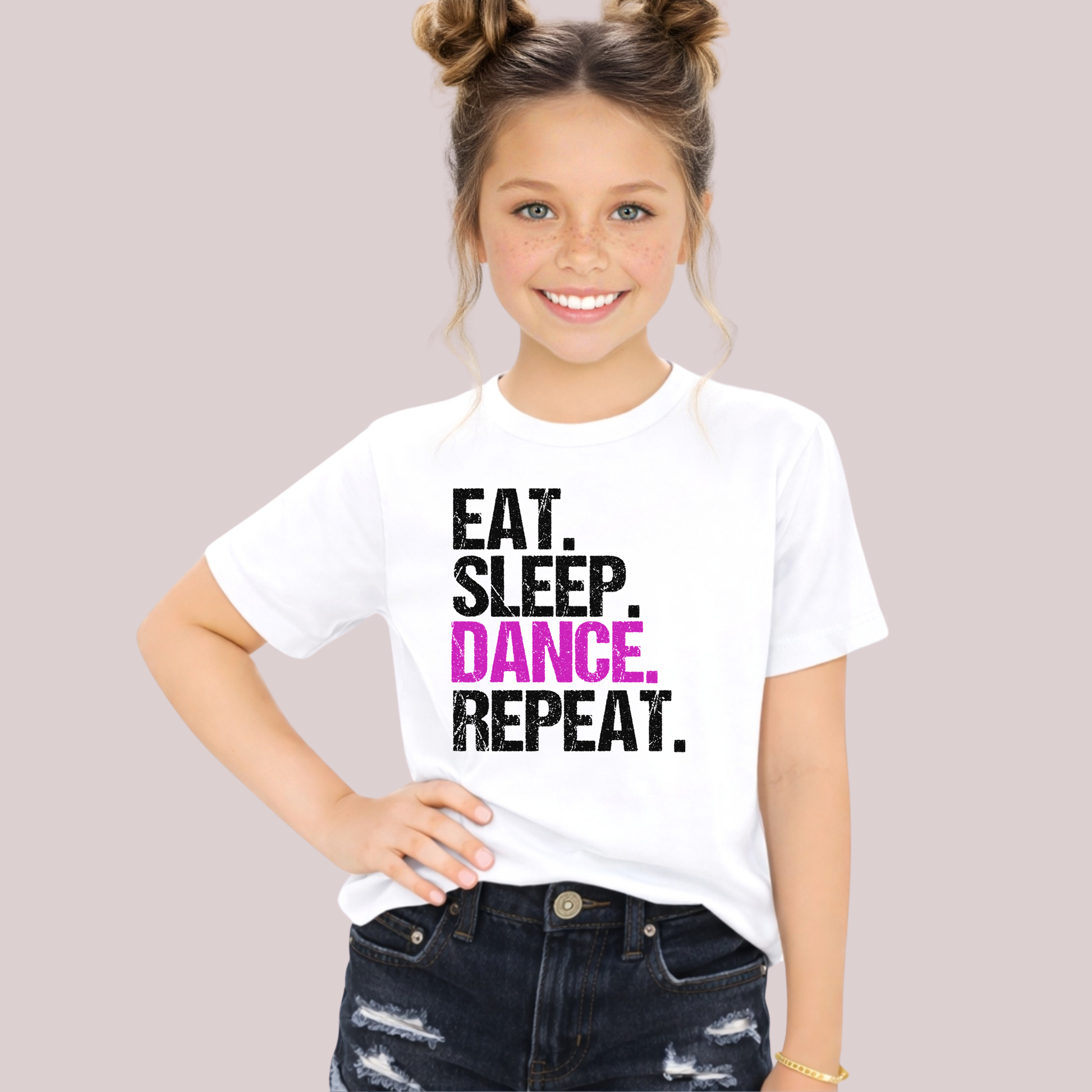 Young girl wearing a white t-shirt with 'Eat. Sleep. Dance. Repeat.' text on a plain background