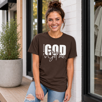 Woman wearing a brown No Worries God Got Me T-shirt with bold white graphic lettering outside a boutique.