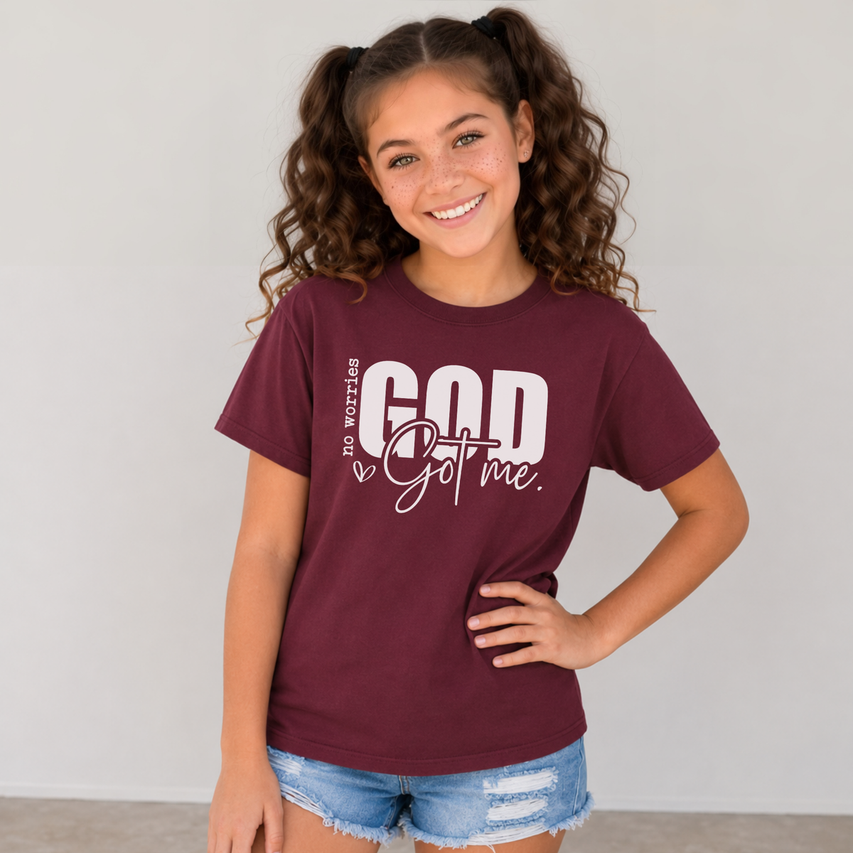 Maroon No Worries God Got Me youth T-shirt with bold white Christian faith graphic.
