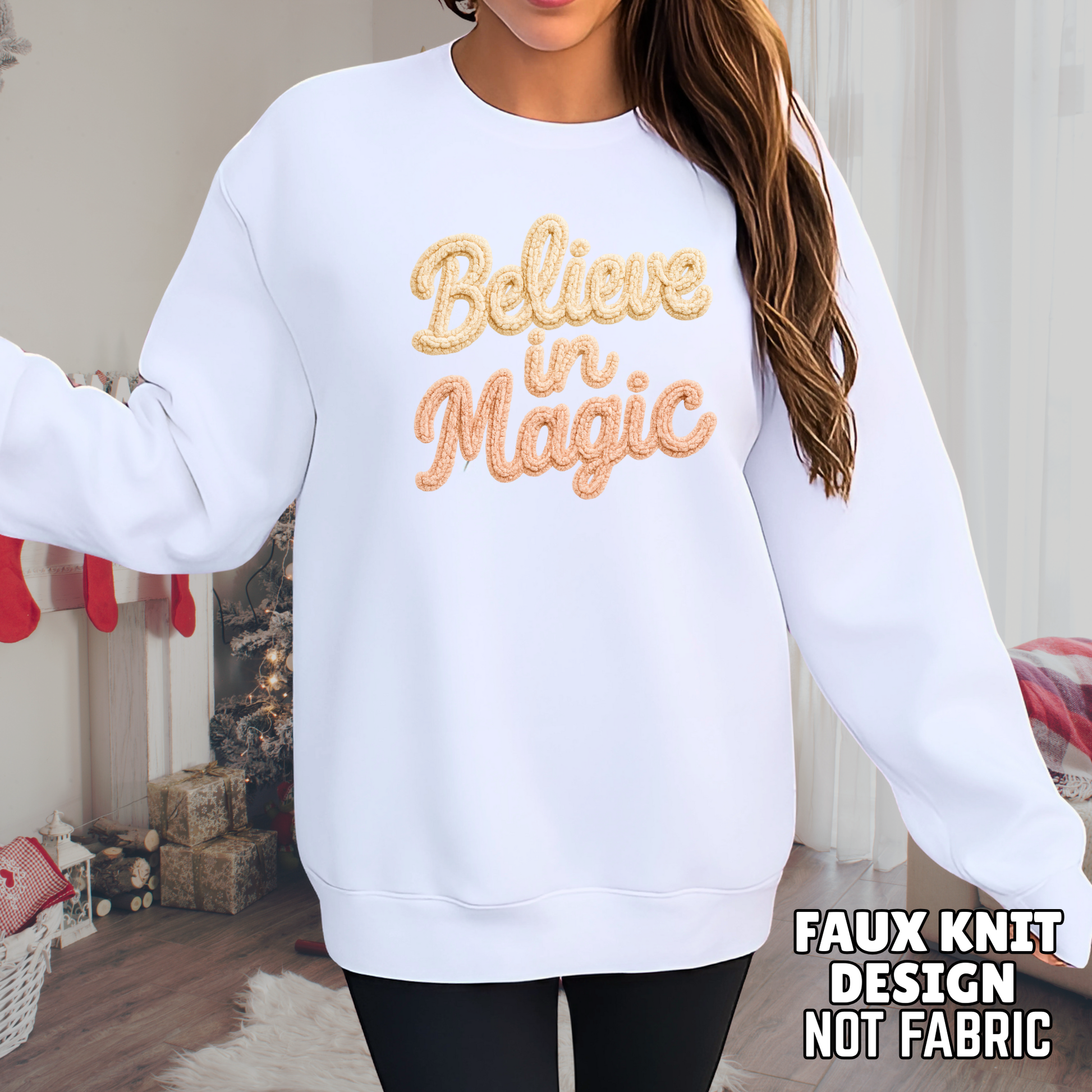 White sweatshirt with 'Believe in Magic' text in gold, worn by a person indoors.