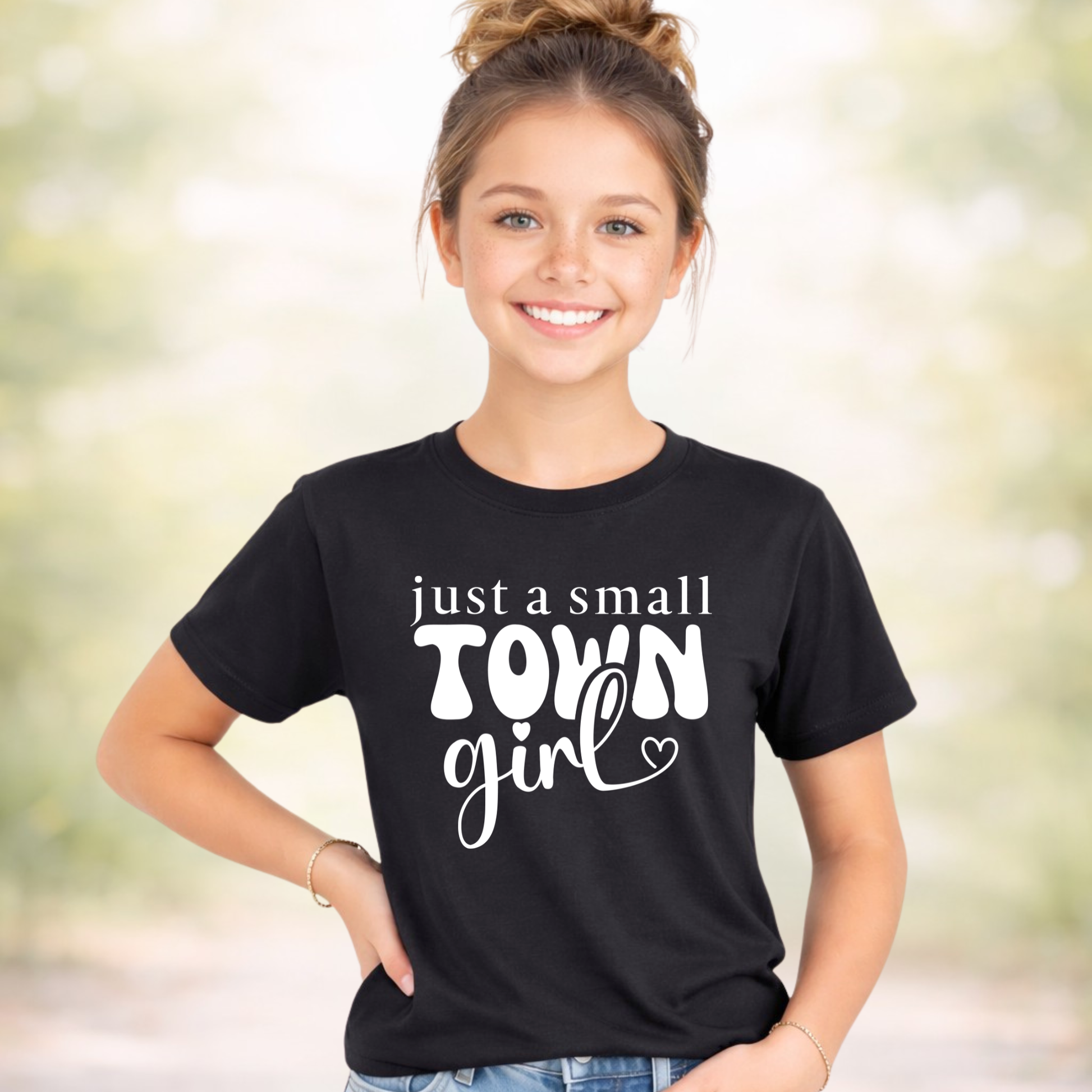 Youth girl wearing black t-shirt with “just a small town girl” graphic design, cute trendy kids shirt, casual outfit