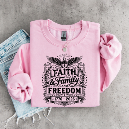 Pink sweatshirt with 'Faith & Family & Freedom 1776-2026' text on a concrete surface