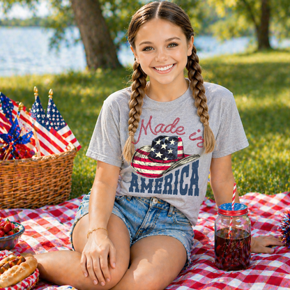 Girl sitting at a picnic with a 'Made in America' shirt, surrounded by American flags and food.