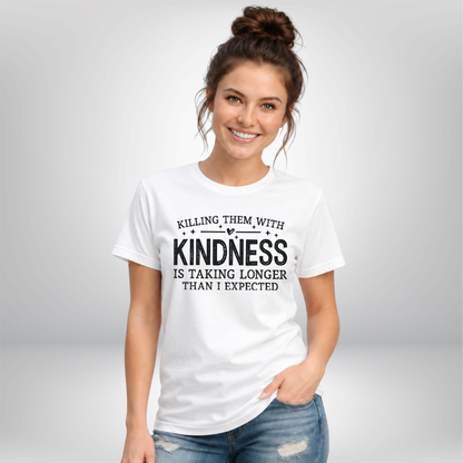 Woman against a gray background wearing a white Killing Them With Kindness T-shirt with black lettering.