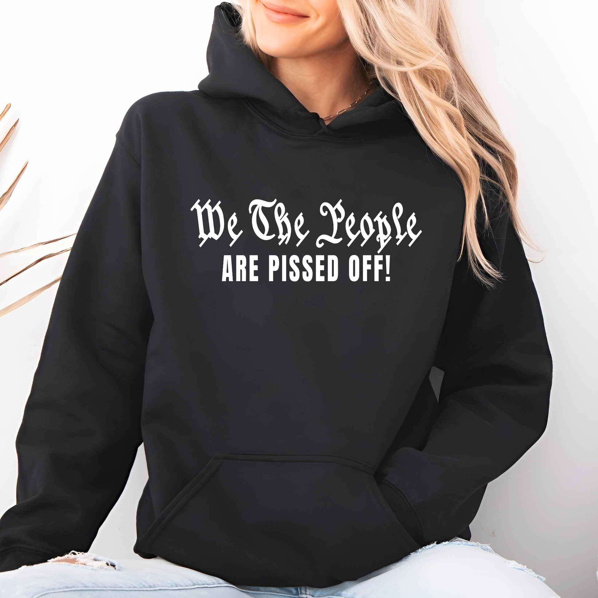 Person wearing a black hoodie with text 'We The People ARE PISSED OFF!' on a light background