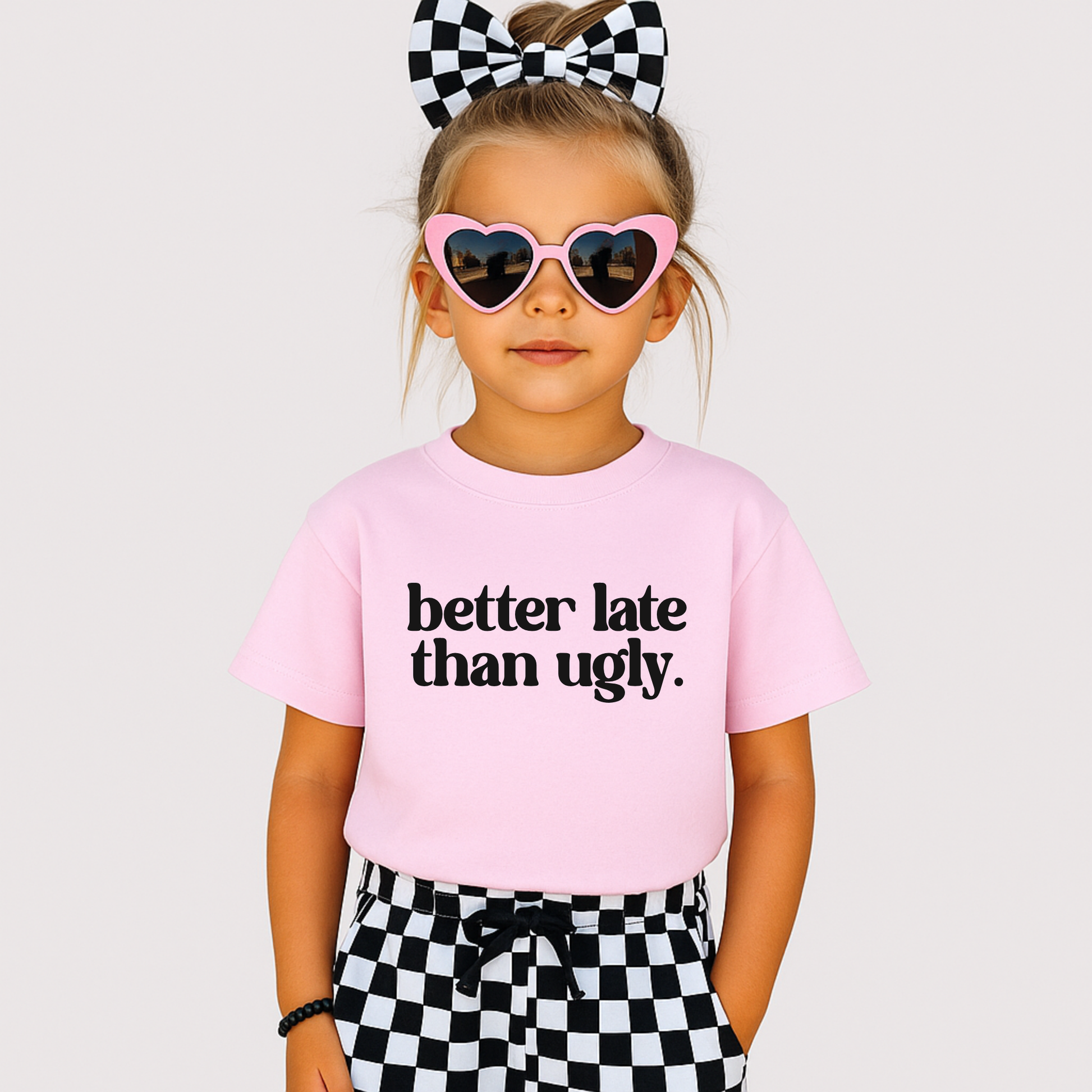 Tween girl in pink tee and checker bow with “Better Late Than Ugly” text – trendy youth fashion