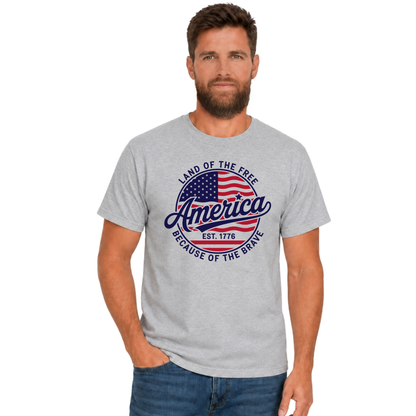 Male model wearing a sports gray T-shirt with a red, white, and blue circular America graphic reading Land of the Free, Est. 1776, and Because of the Brave.