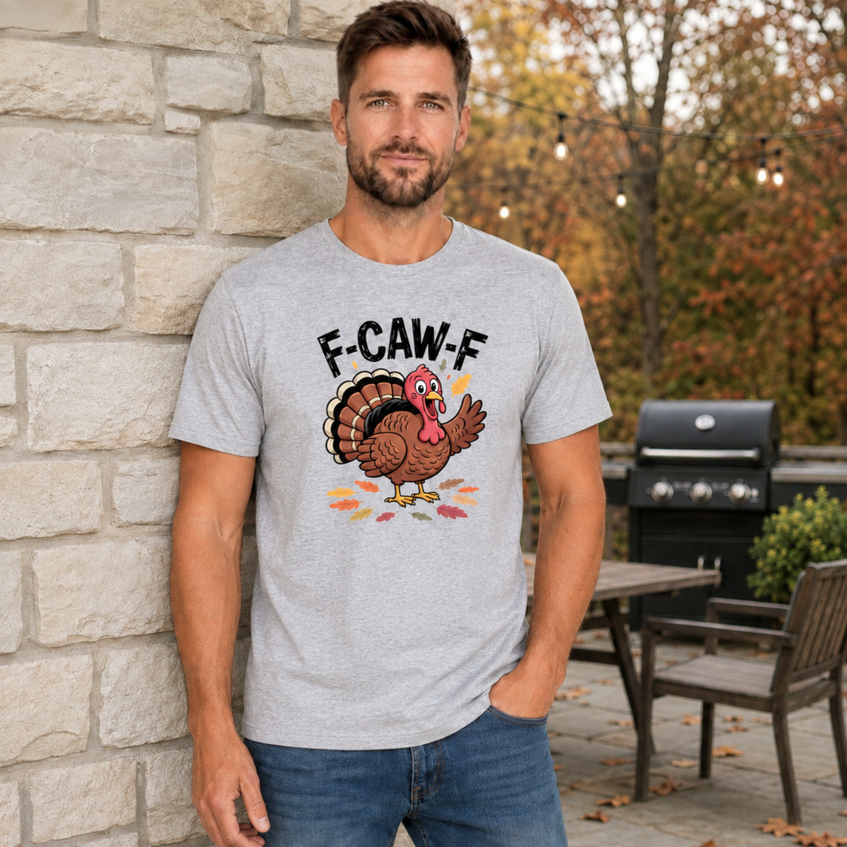Man wearing a sports gray T-shirt with a colorful F-CAW-F turkey graphic in a fall patio setting.