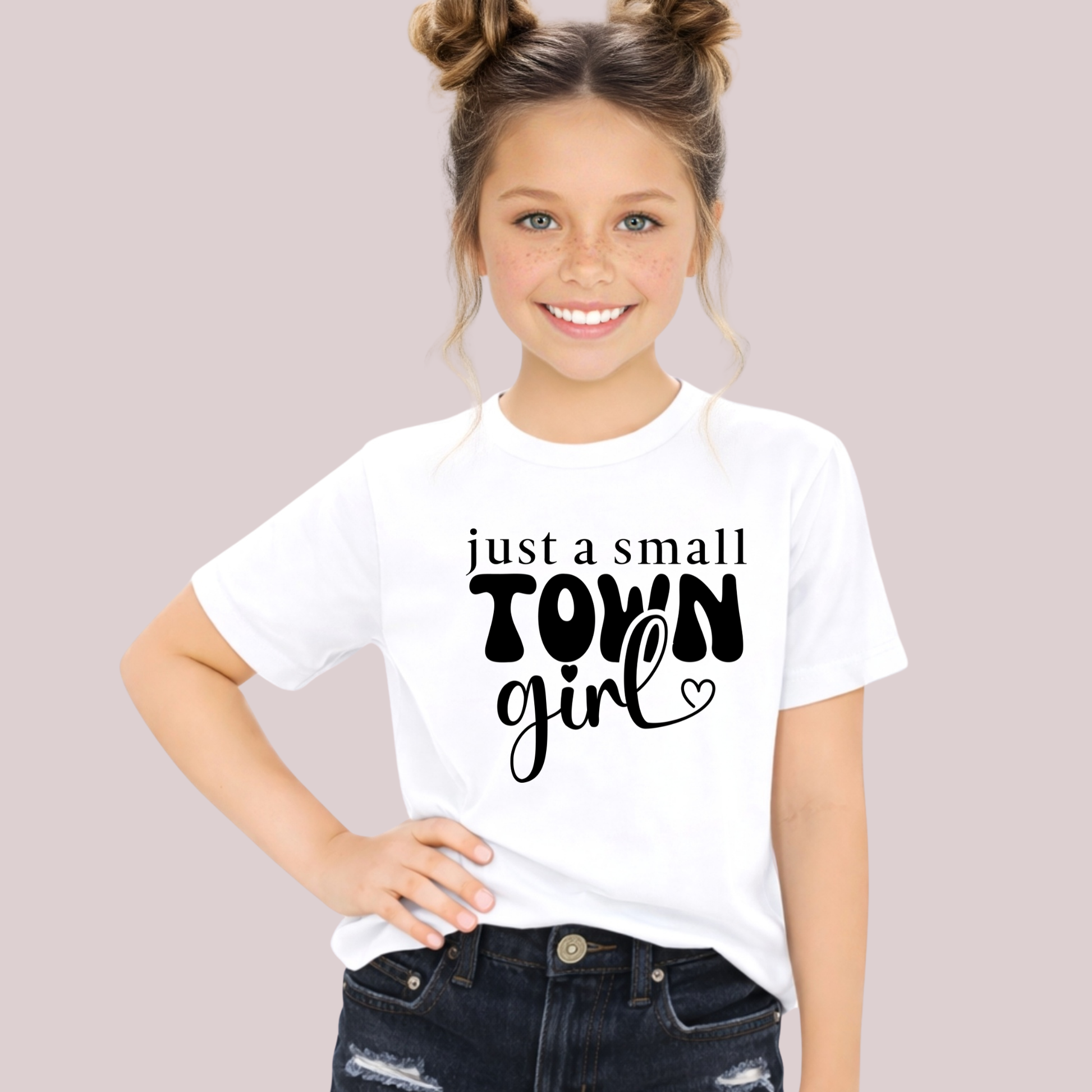 Young girl wearing a white t-shirt with 'just a small town girl' text on a plain background