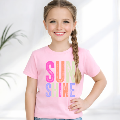 Young girl wearing a pink t-shirt with 'SUNSHINE' in colorful letters on a white background