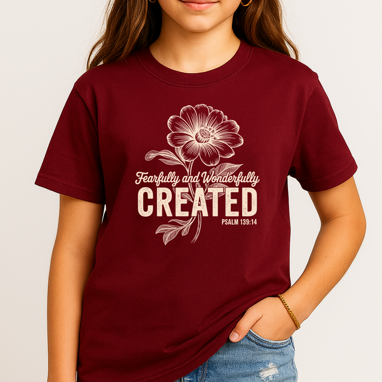 Youth girl wearing maroon t-shirt with Fearfully and Wonderfully Created floral design standing casually