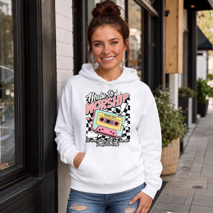 Woman wearing a white Made to Worship hoodie with a retro cassette graphic outside a storefront.