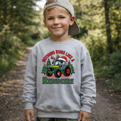 Child wearing a Christmas-themed sweatshirt with a tractor and reindeer design in a forest setting.