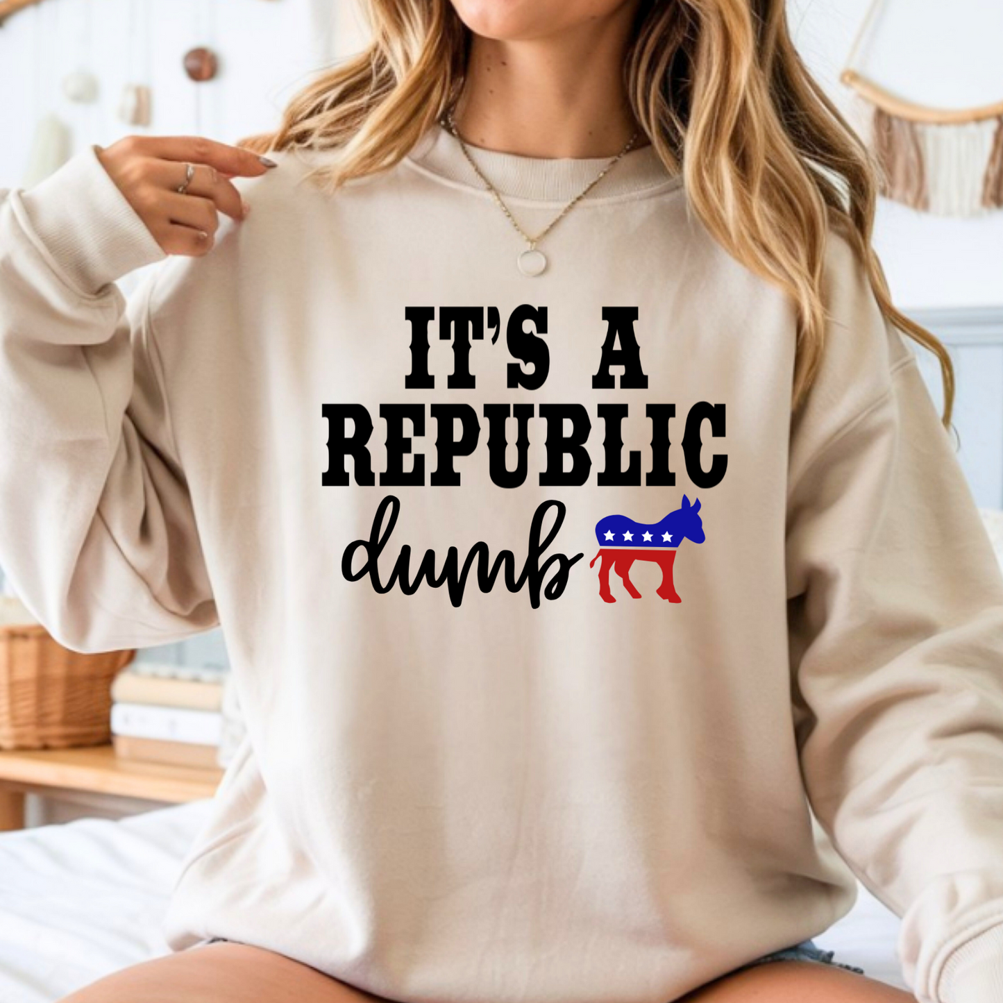 Woman wearing cream unisex t-shirt with “It’s a Republic Dumb” political graphic front view